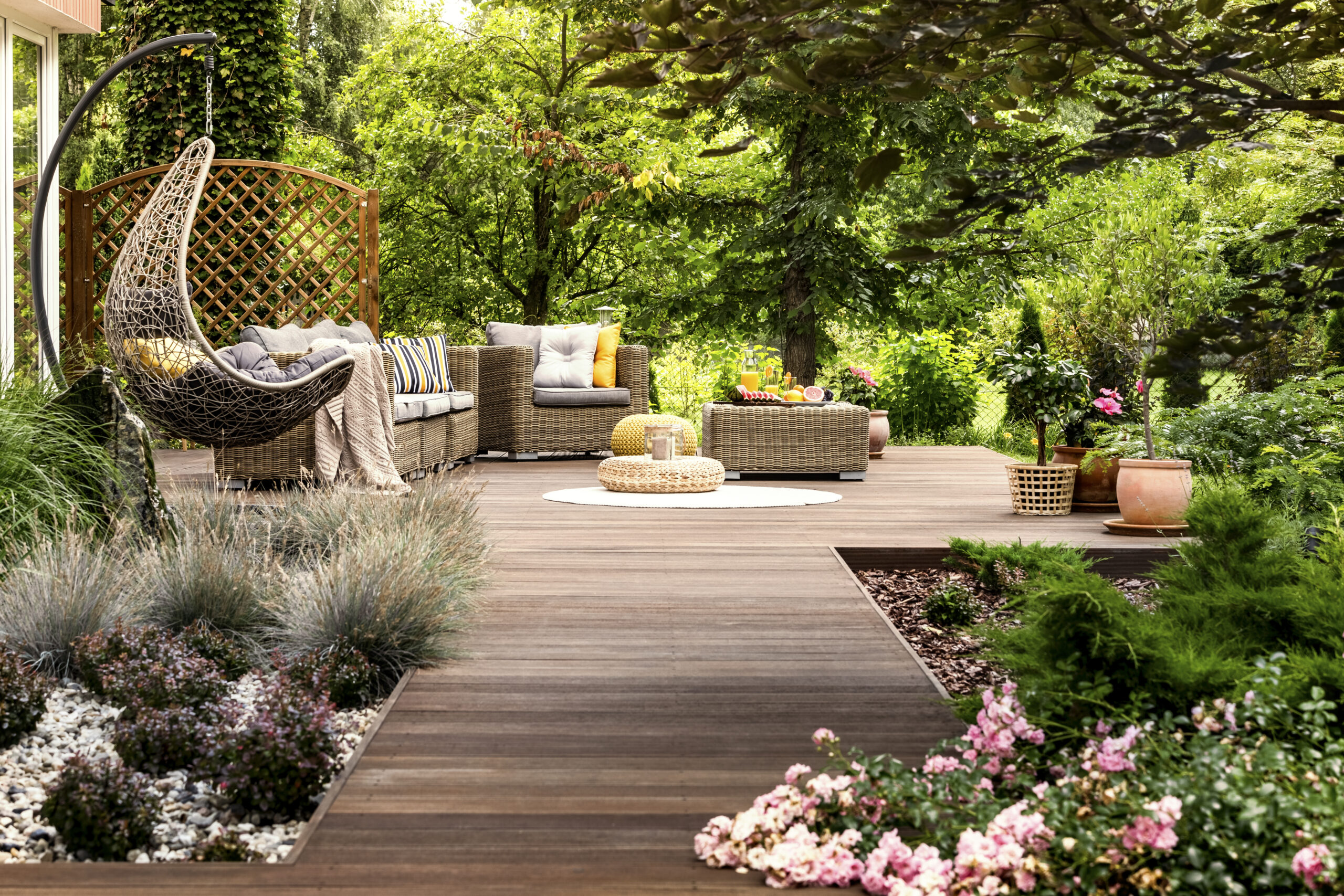 Beautiful wooden terrace with garden furniture surrounded by greenery on a warm, summer day